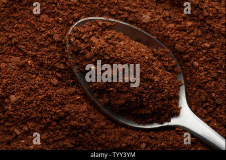 Close up of coffee in spoon above top view on fresh ground Stock Photo