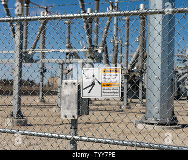 High voltage warning sign showing danger of electrocution on a chain link fence surrounding an electrical substation supplying electricity Stock Photo