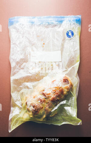 Raw roastbeef meat  prepared, caparisoned with pig caul fat and rosemary inside a sous vide bag ready to be cooked with a rooner , top view  over a br Stock Photo