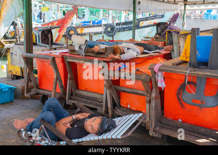 KOTA KINABALU BORNEO - MAY 31 2019; Fishermen asleep on docks near city fishing fleet moored at docks ready to head out again to catch Stock Photo