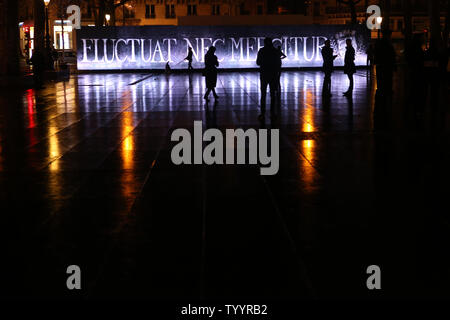 People walk past a lit panel bearing the Latin motto of the city of Paris: 'Fluctuat Nec Mergitur' (Tossed but Not Sunk) as people gather to pay tribute to the victims of last January's attacks at Republic Square in Paris, France, on January 10, 2016, marking the one year anniversary of the series of shooting against Charlie Hebdo weekly newspaper and the Hyper Casher grocery store which claimed 17 lives. .    Photo by Maya Vidon-White/UPI Stock Photo