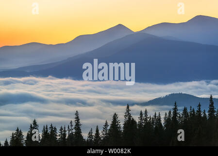 Mountain ranges silhouettes against beautiful sky before sunrise with clouds below Stock Photo