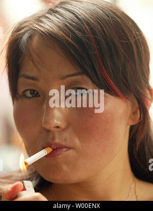 A Chinese woman lights up a cigarette at a cafe in downtown Beijing, July  14, 2006. The Chinese government has called for stronger measures to curb  smoking in the world's biggest cigarette
