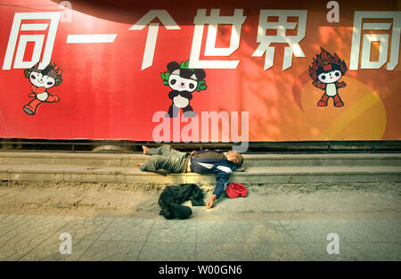 A homeless man lays passed-out in front of an advertisement promoting the 2008 Beijing Olympics in Shenyang, China on September 13, 2007. (UPI Photo/Stephen Shaver) Stock Photo