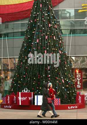 Chinese shoppers walk past a popular fashion shopping mall, adorned with a Christmas tree by Levi's and decorated with a giant Coca-cola advertisement, in Beijing, China on December 28, 2007.   American-based companies are racing to China in hopes of cashing-in on the massive, red-hot consumer market serving 1.3 billion Chinese consumers.    (UPI Photo/Stephen Shaver). Stock Photo