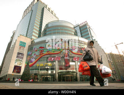 A Chinese shopper leaves a popular fashion shopping mall, adorned with a Christmas tree by Levi's and decorated with a giant Coca-cola advertisement, in Beijing, China on December 28, 2007.   American-based companies are racing to China in hopes of cashing-in on the massive, red-hot consumer market serving 1.3 billion Chinese consumers.    (UPI Photo/Stephen Shaver). Stock Photo