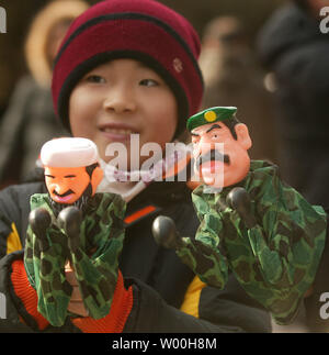 A young Chinese boy boxes with his mom using hand puppets of Osama Bin Laden and Saddam Hussein as holiday crowds enjoy the first day of the Chinese New Year at one of Beijing's main cultural parks, full of both toy and food vendors, on February 07, 2008.  China welcomed in the Year of the Rat Thursday with a bonanza of fireworks and festivals, but the celebrations for many were subdued due to ferocious cold weather that kept them from their families.   (UPI Photo/Stephen Shaver) Stock Photo