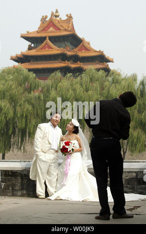 A Chinese couple, dressed in Western style wedding outfits, pose for wedding photographs in front of the Forbidden City in Beijing on October 10, 2008.  Many Chinese couples still are married in traditional Chinese ceremonies, but like to have wedding style photographs taken also.    (UPI Photo/Stephen Shaver) Stock Photo