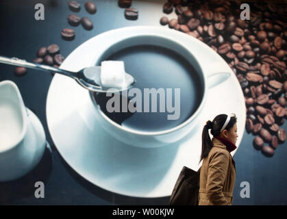 A Chinese woman walks past a giant coffee shop advertisement in downtown Beijing February 07, 2009.  In tea-loving China, having a cup of coffee in a gourmet coffee lounge is fast becoming a symbol of status for the young and affluent in the cities.  (UPI Photo/Stephen Shaver) Stock Photo