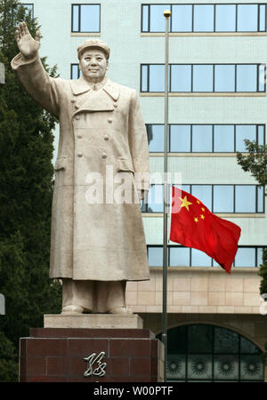 China's national flag flies at half-mast in next to a giant statue of former helmsman Mao Zedong in front of a university in Beijing on April 21, 2010.  China held a three-minute period of silence Wednesday, announcing a day of mourning for the Yushu quake victims where over 2,000 people died.     UPI/Stephen Shaver Stock Photo