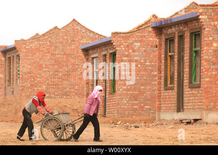 Relocated, poor rural farmers, under the direction of the Ningxia Ecological Migration Program, build a small village for resettlement in Yongning County, a frontier area in the northwestern province Ningxia Hui Autonomous Region on September 23, 2011.  Ningxia has built 25 migration settlements since 1983, allocating over 55,000 hectares of arable land to 412,000 poverty-stricken farmers.  The government-sponsored partial migration project to relocate poor farmers living in the arid and frigid southern mountains to the Yellow River irrigation areas is aimed at fundamentally changing and impro Stock Photo