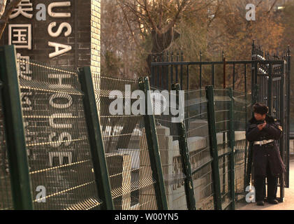 A Chinese security guard rests in the sun next to a fence surrounding an upscale clubhouse named the 'USA House' in central Beijing December 23, 2011. Western-style clubs, restaurants, shopping centers and resorts catering to China's new rich are springing up all over China's major urban centers.      UPI/Stephen Shaver Stock Photo