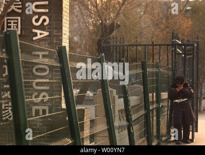 A Chinese security guard rests in the sun next to a fence surrounding an upscale clubhouse named the 'USA House' in central Beijing December 23, 2011. Western-style clubs, restaurants, shopping centers and resorts catering to China's new rich are springing up all over China's major urban centers.      UPI/Stephen Shaver Stock Photo