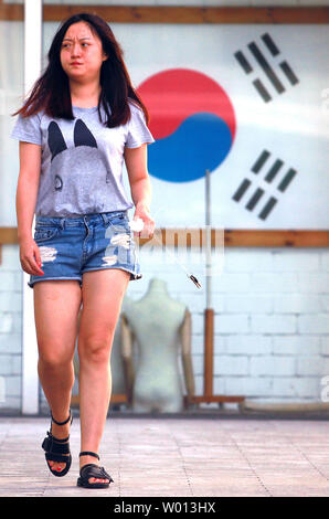 A Chinese woman walks past a travel agency specializing in trips and packages to South Korea in downtown Beijing on August 27, 2013.  South Korea remains one of the top tourist destinations for Chinese, despite recurrent tensions between the two countries.       UPI/Stephen Shaver Stock Photo