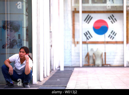 A Chinese woman talks on a phone next to a travel agency specializing in trips and packages to South Korea in downtown Beijing on August 27, 2013.   South Korea remains one of the top tourist destinations for Chinese, despite recurrent tensions between the two countries.    UPI/Stephen Shaver Stock Photo
