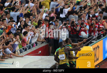 Jamaica's Nickel Ashmeade, Asafa Powell, Usain Bolt and Nesta Carter pose for selfies with phones from the crowd after winning the 4x100 meters relay final at the IAAF World Championships being hosted by Beijing on August 29, 2015.  Jamaica won with a time of 37.36 seconds, followed by China (38.01) and Canada (38.13) in third.  USA was disqualified.   Photo by Stephen Shaver/UPI Stock Photo