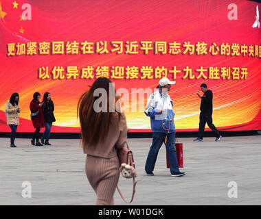 Chinese walk past a giant electronic monitor displaying slogans promoting President Xi Jinping and the Communist Party at an office complex in downtown Beijing on October 29, 2017.  China's Communist Party elevated Xi to the same status as the nation's founding father, Mao Zedong, by writing his name and ideas into the party constitution.      Photo by Stephen Shaver/UPI Stock Photo