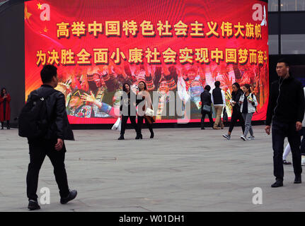 Chinese walk past a giant electronic monitor displaying slogans promoting President Xi Jinping and the Communist Party at an office complex in downtown Beijing on October 29, 2017.  China's Communist Party elevated Xi to the same status as the nation's founding father, Mao Zedong, by writing his name and ideas into the party constitution.      Photo by Stephen Shaver/UPI Stock Photo