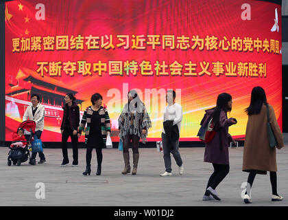 Chinese walk past a giant electronic monitor displaying slogans promoting President Xi Jinping and the Communist Party at an office complex in downtown Beijing on October 29, 2017.  China's Communist Party elevated Xi to the same status as the nation's founding father, Mao Zedong, by writing his name and ideas into the party constitution.      Photo by Stephen Shaver/UPI Stock Photo