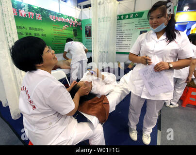 A Chinese nurse applies traditional Chinese medicine  (TCM) to a visitor at a exhibition center in Beijing on May 31, 2018.  TCM, which includes acupuncture and herbal potions, has long been attributed to the long life spans of Chinese.   Photo by Stephen Shaver/UPI Stock Photo