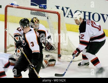 PHI2000011503 - 15 JANUARY 2000 - PHILADELPHIA, PENNSYLVANIA, USA: Flyers'  Keith Jones (#20) is tripped up by New Jersey's John Madden (#11)as they go  for the puck behind the New Jersey net