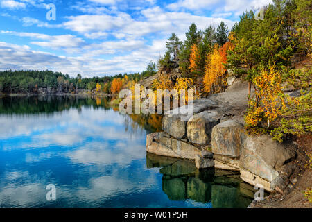 Beautiful lake during autumn day with golden color trees on rocky shore Stock Photo