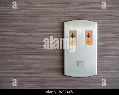 Digital number and down arrow on metallic elevator call panel on wooden pattern wall background with copy space. Stock Photo