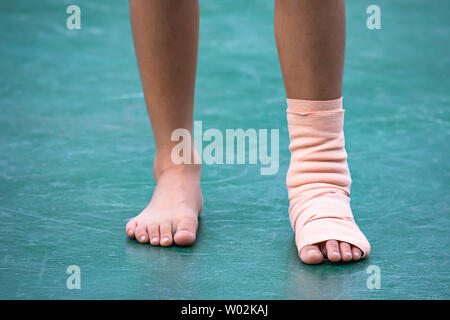 The  gauze bandages around the Ankle boy and leg swelling from inflammation On a green background. Stock Photo