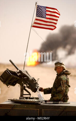 A soldier from the Army helps to guard the Rumelia Oil Field in southern Iraq as firefighters prepare massive water lagoons in the desert to extinguish the last two fires at sabotaged oil wells by the fleeing Iraqi Army on April 2, 2003. Teams from Boots & Coots International Well Control and the Kuwait Oil Co. failed to put out the blazes earlier this week, using water from smaller storage tanks.   (UPI Photo/Chris Corder) Stock Photo