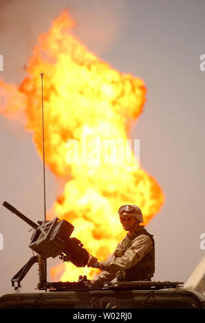 A soldier from the Army helps to guard the Rumelia Oil Field in southern Iraq as firefighters prepare massive water lagoons in the desert to extinguish the last two fires at sabotaged oil wells by the fleeing Iraqi Army on April 2, 2003. Teams from Boots & Coots International Well Control and the Kuwait Oil Co. failed to put out the blazes earlier this week, using water from smaller storage tanks.   (UPI Photo/Chris Corder) Stock Photo