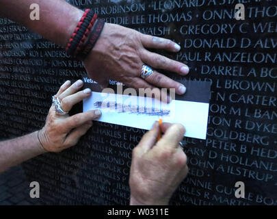 Veterans etch the names of their friends inscribed on the  Vietnam Veterans Memorial on the 50th anniversary of the Vietnam War on May 26, 2012 in Washington, DC.   More than 58,000 names of the servicemen who were killed or missing in the war are engraved on The Wall.  UPI/Pat Benic Stock Photo