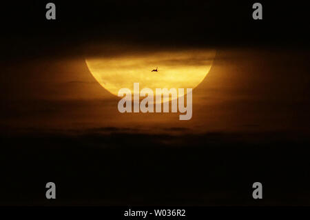 An airplane passes by a supermoon that rises up from behind the Manhattan Skyline partially obstructed by clouds after sunset in New York City on November 14, 2016. The most spectacular supermoon since 1948 lights up the sky on Tuesday morning and evening, appearing 14 per cent bigger and 30 percent brighter than usual. November's supermoon, a term used to describe a full moon is at its perigee or closest point to Earth during the lunar orbit, will be the biggest and brightest supermoon to rise in almost 69 years. A full moon won't come this close to Earth again until November 25, 2034. Photo Stock Photo