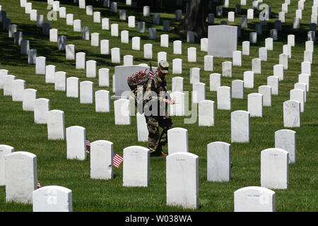 U.S. soldier places flags near the tombstone of a fallen veteran at Arlington National Cemetery during the 'Flags In' tradition in Arlington, Virginia on May 24, 2018.  The 3rd U.S. Infantry Regiment (The Old Guard) has honored veterans for more than 60 years by placing flags at their gravesites. About 900 soldiers place 228,000 flags in front of gravestones in four hours. Photo by Pat Benic/UPI Stock Photo