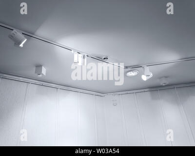 perspective view of empty gallery interior wall with row of ceiling spotlights Stock Photo