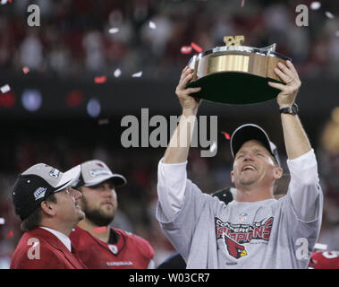 Arizona Cardinals owner Bill Bidwill (L) holds the George Halas Trophy as  commentator Terry Bradshaw (second from left,) interviews team president  Michael Bidwill (third from left) as coach Ken Whisenhunt (R) looks