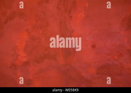 Red painted wall background. Grunge retro aged outside surface from cement or concrete painted in red color Stock Photo
