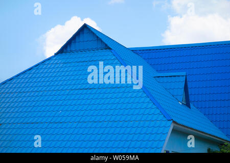 Blue tiled roof of house on sky background in day time. Object of modern townhouse or other real estate construction Stock Photo