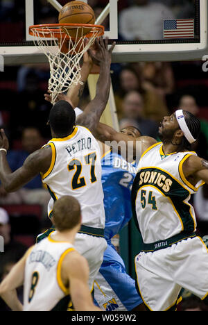 Denver Nuggets' Anthony Carter (C) hits a underneath the basket layup through defending Seattle SuperSonics' Johan Petro, of France, (L) and Chris Wilcox (R) during the first half at the Key Arena in Seattle on February 27, 2008. (UPI Photo/Jim Bryant) Stock Photo