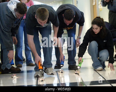 Fox High School students (L to R) A.J. Collier, Anthony Lannigan, Dan Paliasky and Melissa Jones use flashlights to direct their small robotsduring a class on robots at Saint Louis University's Parks College of Engineering and Aviation as part of National Engineers Week in St. Louis on February 26, 2004.Students assembled the robot consisting of two light sensors and two motors. The students learn to navigate a race course with the use of the flashlight, which controls the sensors. (UPI Photo/Bill Greenblatt) Stock Photo