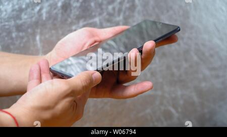 Man holding Huawei Mate 20 X smartphone in one hand and showing its display on shining grey background. Studio light flashes on screen Kyiv, Ukraine 1 Stock Photo