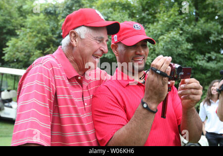 Former college basketball coach Bobby Knight, left, autographs baseballs  while wearing the St. Louis Cardinals colors before their game against the  New York Mets in a spring training Grapefruit League baseball game