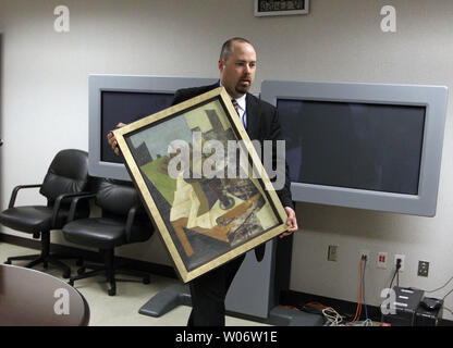 FBI Special Agent Tim Carpenter from the Miami office carries a recovered stolen painting into a room before a press conference in St. Louis on October 20, 2010. The painting was stolen from the home of Clifton Hyatt more than six years ago. The 1926 oil painting by Juan Gris, was taken April 18, 2004 and recovered in Florida. Robert C. Dibartolo of Fort Pierce, Fla., was arrested after showing an undercover FBI employee pictures of the painting. Dibartolo, 68, pleaded guilty in July in federal court in Florida to the sale or receipt of stolen goods and was sentenced Sept. 20 to one year and o Stock Photo