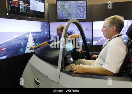 Col. Jack Jackson, a former Marine pilot, is guided onto the deck of an aircraft carrier by Lockheed simulator instructor Rick Royer of Fort Worth, during an inspection of its F-35 Lightning II mobile cockpit demonstrator to employees, state and local elected officials, other stakeholders in Earth City, Missouri on July 20, 2011. With 25 supplier locations in Missouri, the F-35 program currently provides approximately 525 direct and indirect jobs and generates nearly $35.5 million in economic impact across the state. The F-35 Lightning II is an advanced military aircraft. UPI/Bill Greenblatt Stock Photo