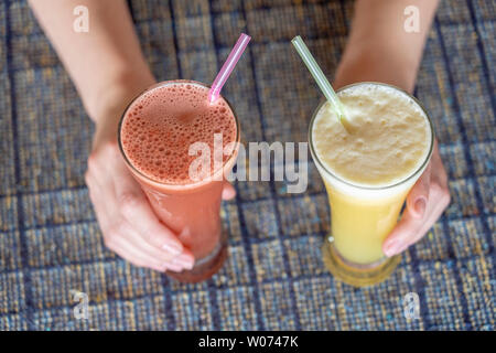 Woman hands holding two glasses with pineapple and watermelon fresh juice, close up, healthy lifestyle concept Stock Photo