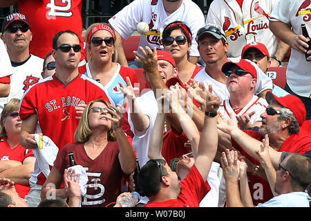 St. Louis Cardinals fans in the center field bleachers reach for a