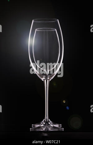 Empty wine glasses on black background, glassware for drinks. Contours and light glare, vertical arrangement Stock Photo