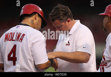 St. Louis Cardinals catcher Yadier Molina has his hand looked at by assistant trainer Chris Conroy after a hard slide into third base during a game against the Pittsburgh Pirates at Busch Stadium on July 9, 2014. The Cardinals have announced that Molina will have surgery on 7/11/2014 to repair a torn ligament in his thumb injured on the play.  Molina, scheduled to be the starting catcher in the 2014 All-Star game, will now be out of action for 10-12 weeks. UPI/Bill Greenblatt Stock Photo