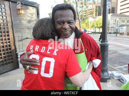 Former St. Louis Cardinals and member of the National Baseball Hall of Fame Lou Brock, hugs longtime fan Gert Booher, while selling newspapers on Old Newsboys Day in Clayton, Missouri on November 17, 2016. Brock and many others collected at street corners on Old Newsboys Day, with funds going to over 200 children's charities in the St. Louis area. Photo by Bill Greenblatt/UPI Stock Photo