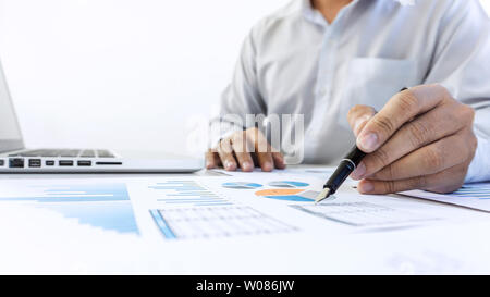 Businessman accountant working audit and calculating expense financial data on graph documents, doing finance in workplace. Stock Photo