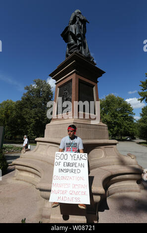 Ted Olguin holds a sign while sitting on the Christopher Columbus statue in Tower Grove Park in St. Louis on Octiober 8, 2018. Several Protesters who would like to see the statue removed, converged at the statue while others gathered that would like to see a plaque added that talked about the history of Columbus killing the indigenous peoples. Olguin represented the American Indian Movement of Missouri, who would like to see a plaque added. Photo by Bill Greenblatt/UPI Stock Photo